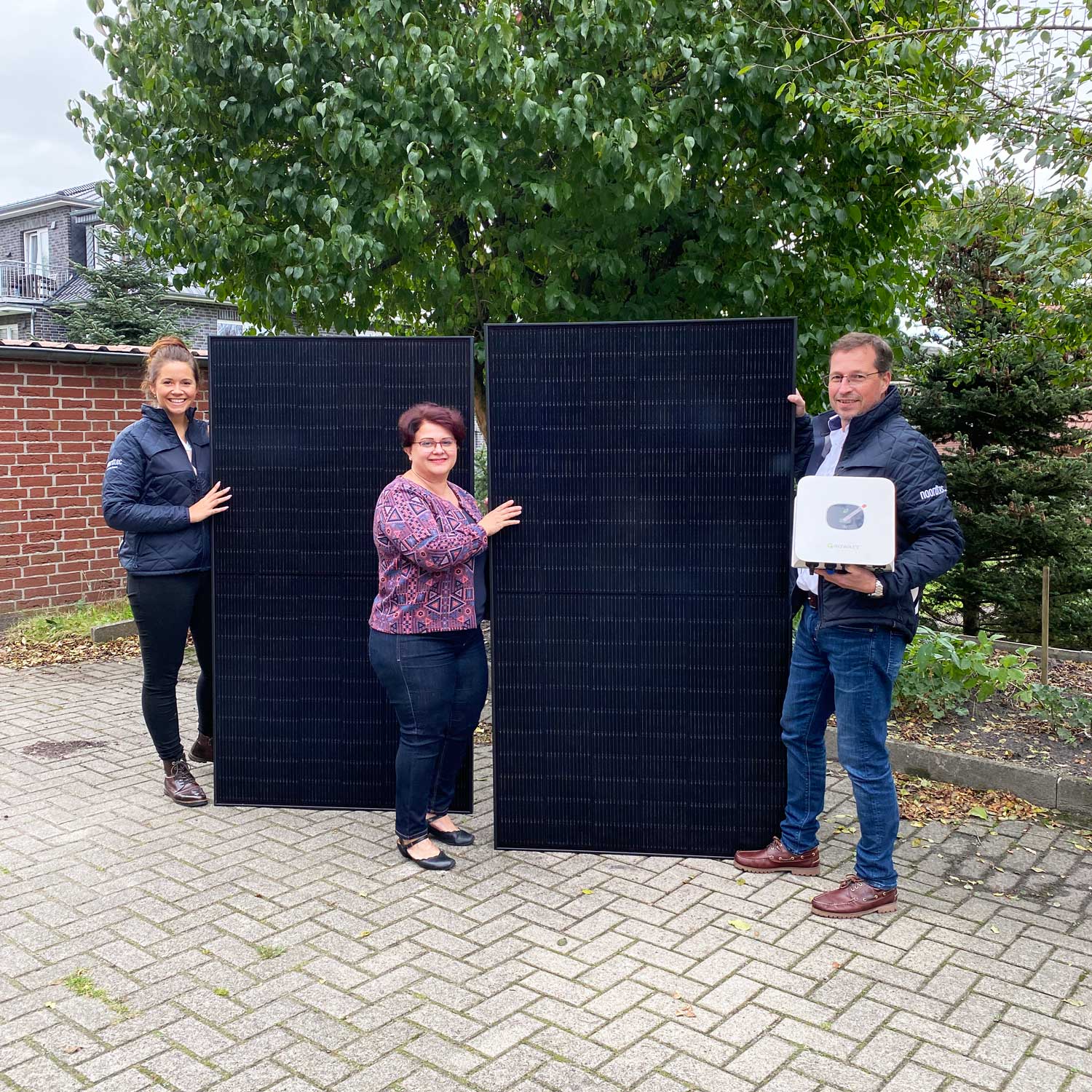 Zwei MitarbeiterInnen von Noordtec und die Gewinnerin des BKWs aus Hude mit zwei Solarmodulen und Wechselrichter
